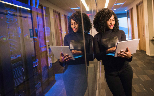 Mulher olhando um notebook com seu reflexo em um vidro