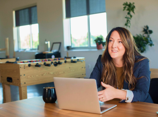 Mulher com notebook conversando com alguém sorrindo em uma sala com alguns jogos